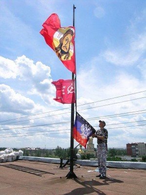 Боевик снимает флаги с здания захваченного горисполкома